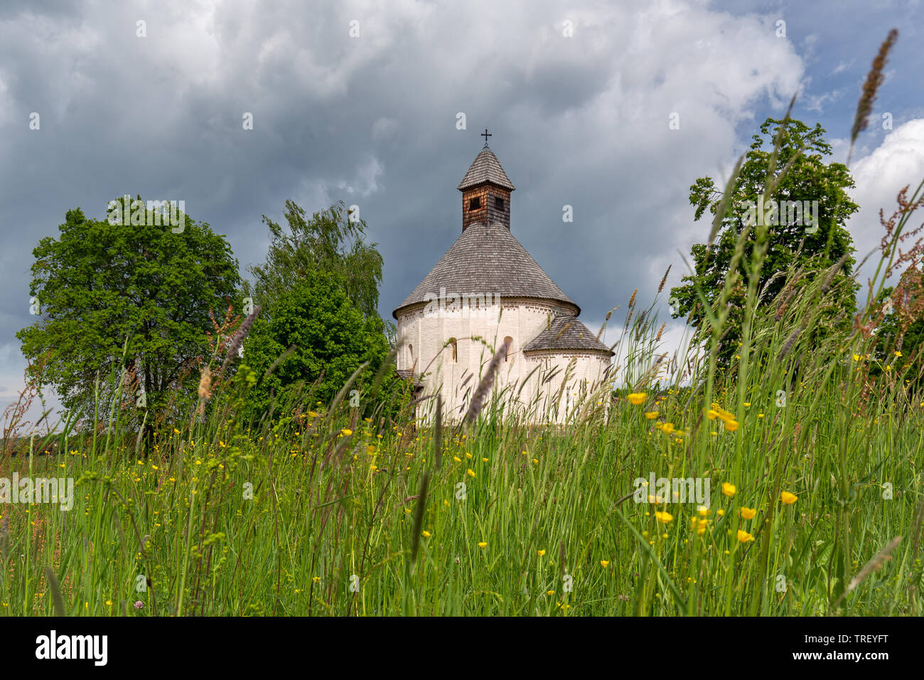 Sankt Nikolaus und Jungfrau Maria Rotunda in Selo, Slowenien. Niedrige perspektivische Ansicht der älteste Rotunde in Slowenien. Frühling Blumen und grüne Bäume um Mo Stockfoto