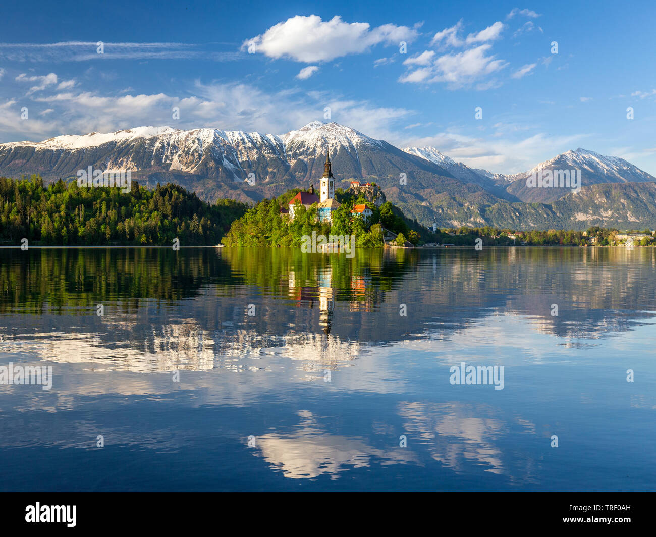 Der See von Bled, Slowenien. Sonnenuntergang, warmes Licht auf assumtion-Kirche auf der Insel in der Mitte des Sees ruhige Szene mit Schnee bedeckte Berge zurück Stockfoto