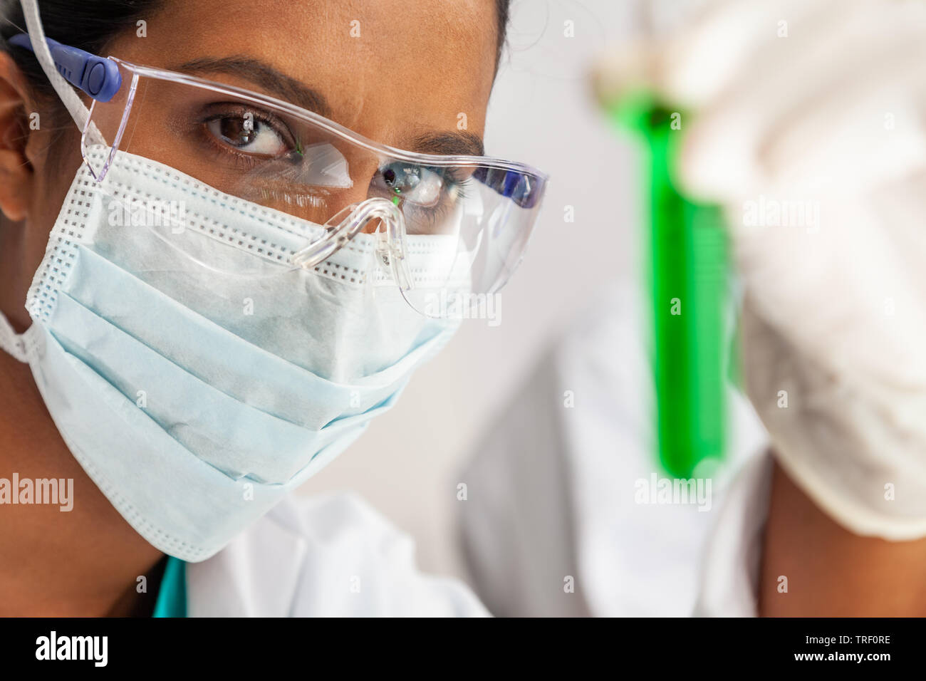 Weibliche Indische asiatische Frau Wissenschaftler oder Arzt in einem Reagenzglas eine grüne Lösung in einer medizinischen Forschung Labor oder Labor Stockfoto