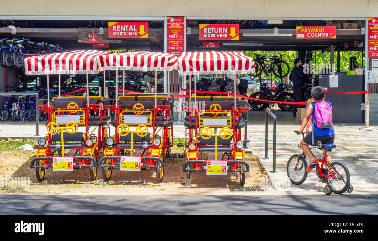 Jungen auf einem Fahrrad mit stützräder vor Fahrradverleih Depot an der East Coast Park Singapur. Stockfoto