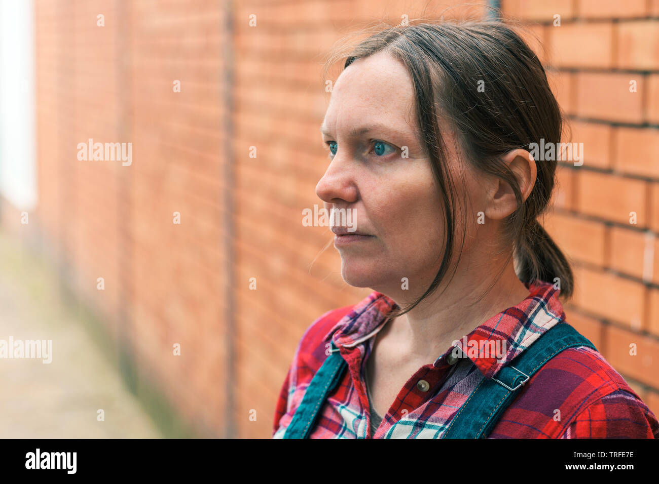Weibliche Landwirt denken. Outdoor Portrait von Erwachsenen kaukasischen stehende Frau vor dem Bauernhaus. Stockfoto