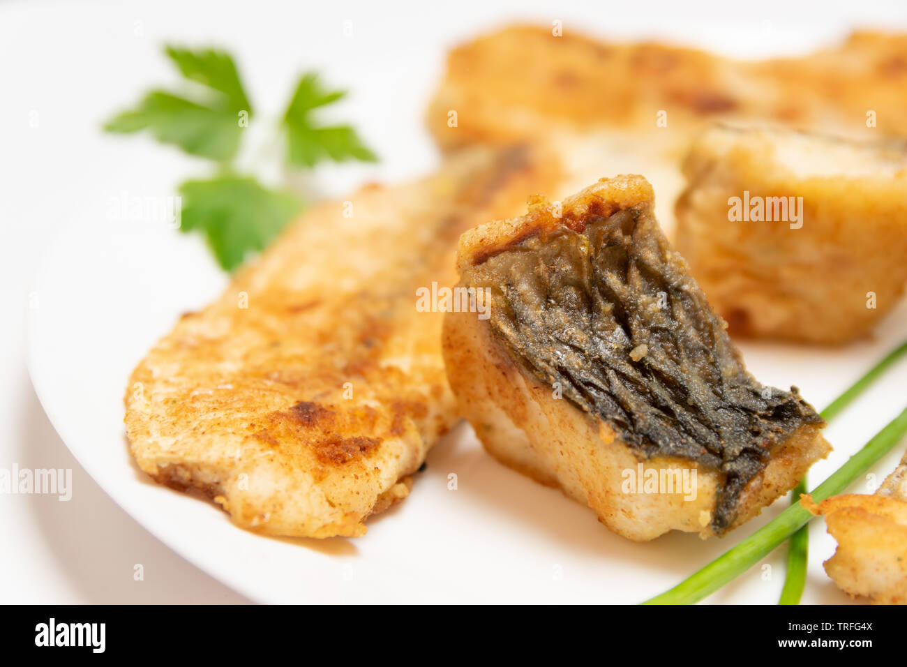Leckeres Essen, Ernährung, Küche und kulinarische Konzept: closeup Stücke gebraten, gebacken, golden und lecker Fisch auf einem weißen Teller. Stockfoto