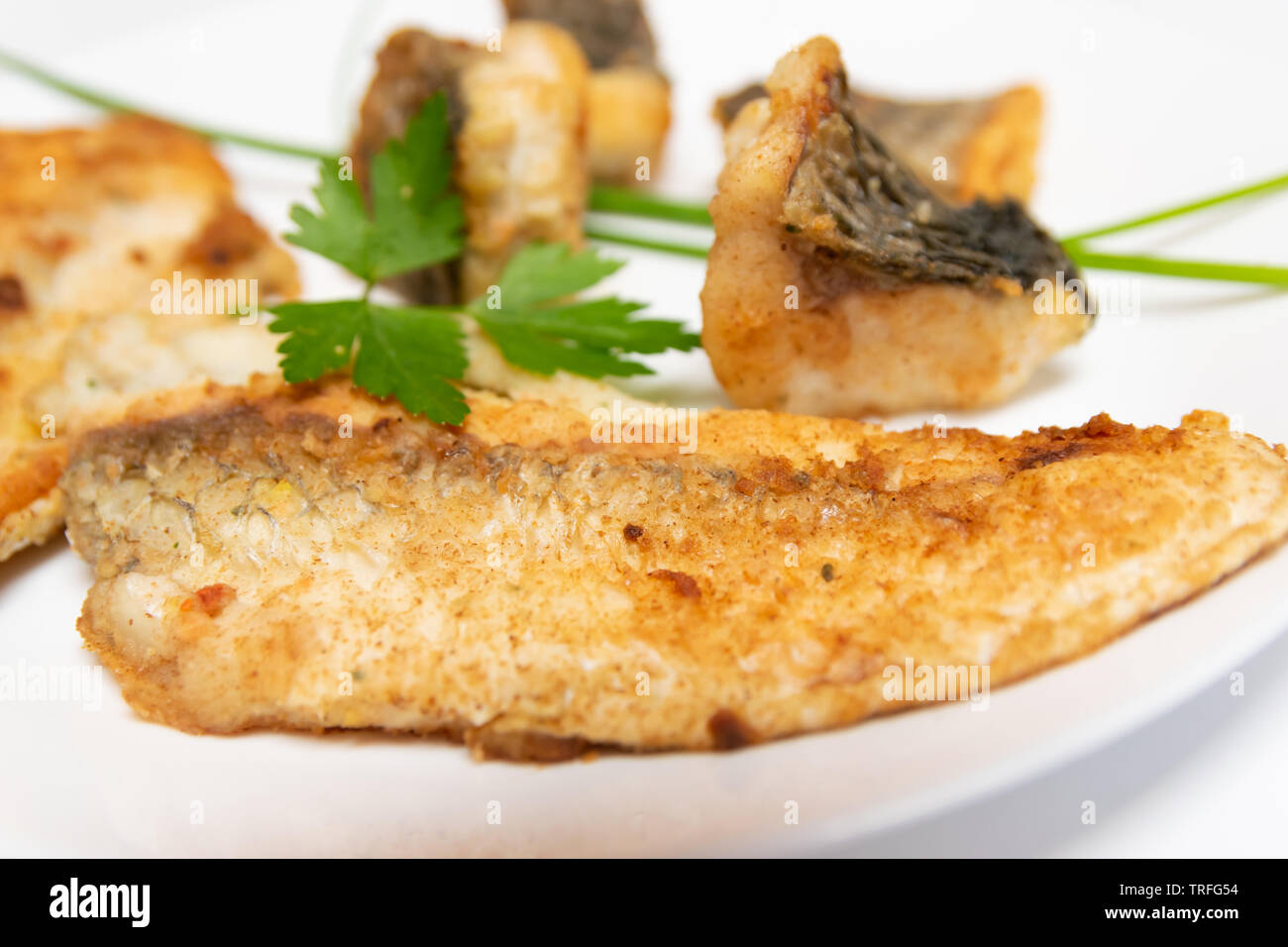Leckeres Essen, Ernährung, Küche und kulinarische Konzept: closeup Stücke gebraten, gebacken, golden und lecker Fisch auf einem weißen Teller. Stockfoto