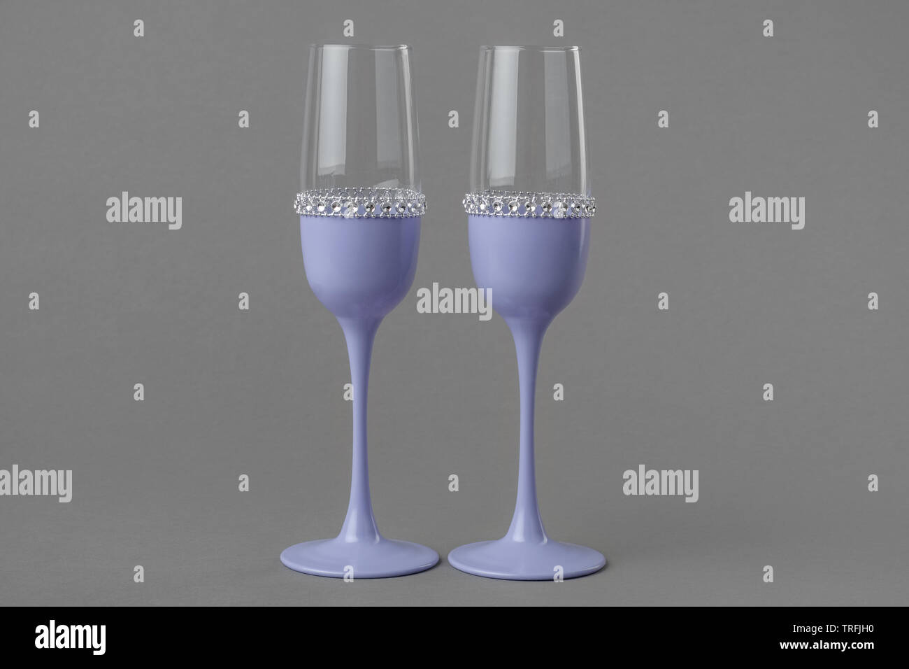 Zwei Hochzeit Weingläser in lila Farbe auf grauem Hintergrund. Stockfoto