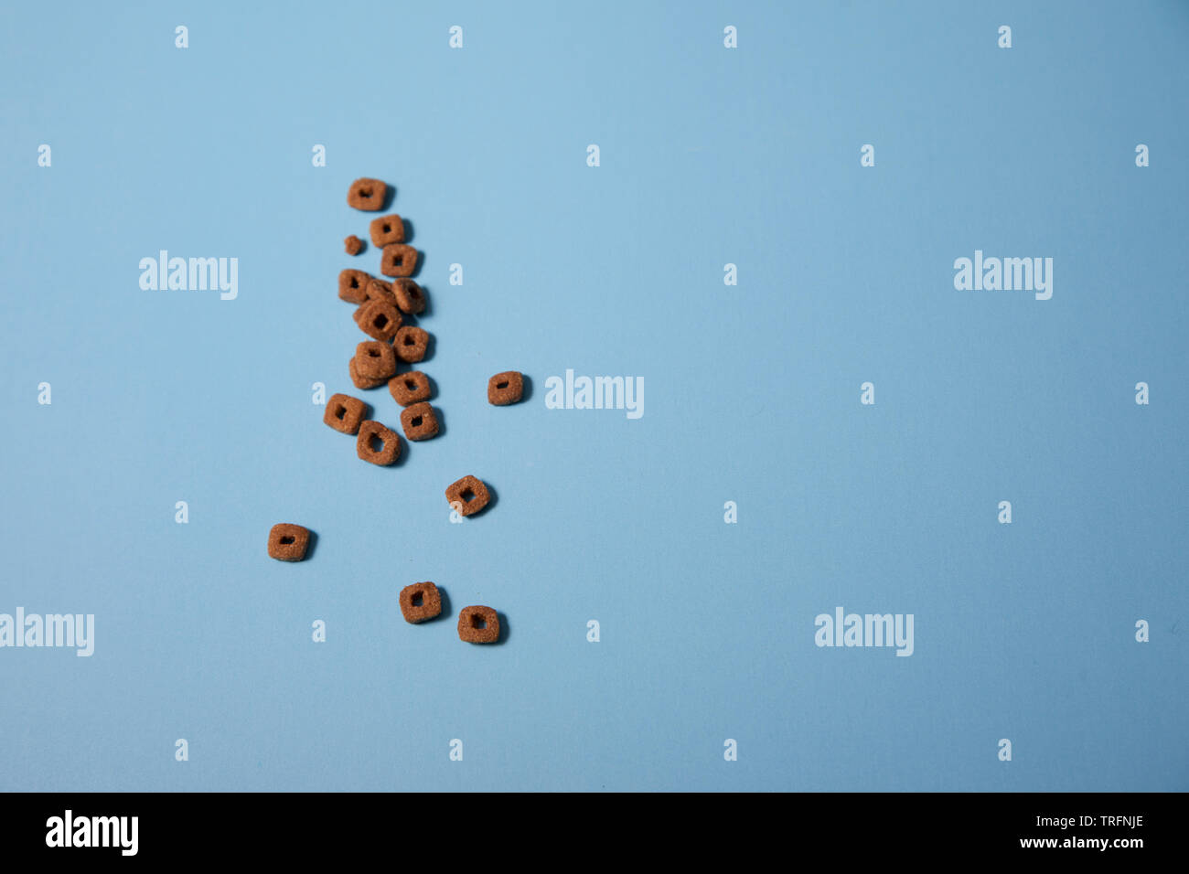 Kleine trocken Katzenfutter auf einem blauen Hintergrund verstreut Stockfoto
