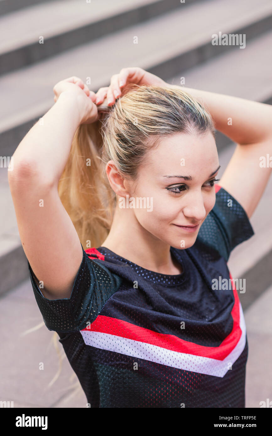 Passende Frau ihr Pony Tail einstellen während eines Trainings in der Stadt Stockfoto