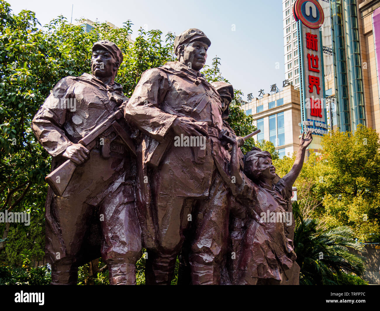 Statue der Volksbefreiungsarmee (PLA) in Nanjing Road, Shanghai, mit der Neuen Welt Emporium Einkaufszentrum im Hintergrund - eine Gegenüberstellung von communis Stockfoto