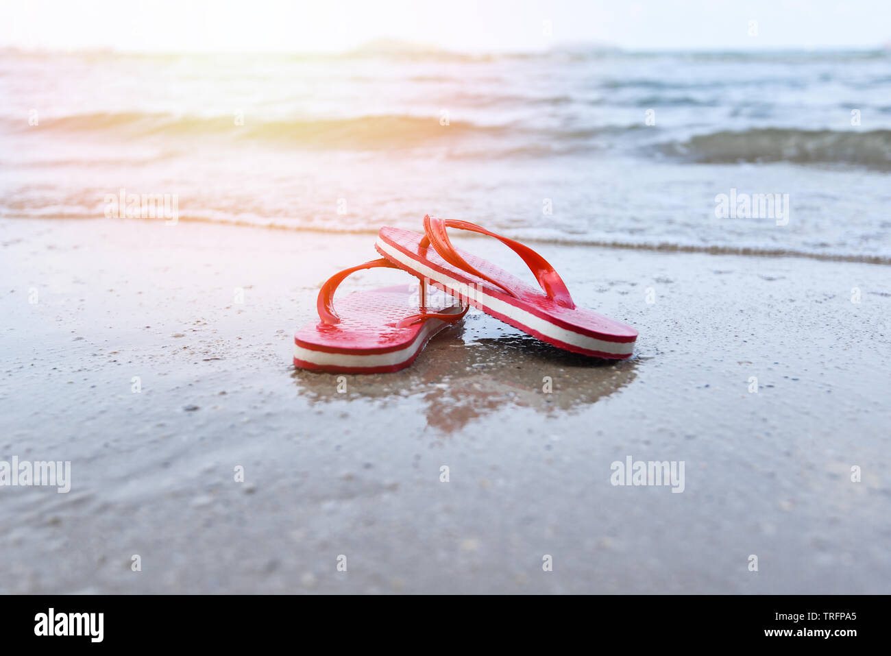 Rote flip flops am Strand mit Sandstrand Meer Ozean und Sonnenlicht  Hintergrund Stockfotografie - Alamy