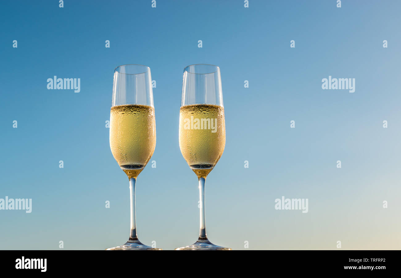 Golden champagner Blasen in Flöte Gläser. Seitliche Sicht auf zwei Gläser Sekt auf blauen Himmel Hintergrund isoliert. Stockfoto