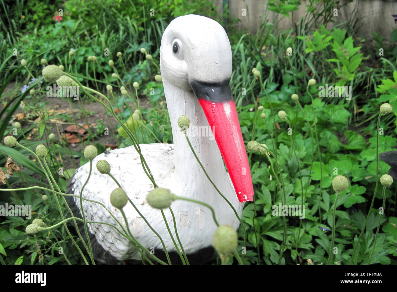 Weiße Vogel mit rotem Schnabel Dekor Skulptur im Garten im Hinterhof. Stork liefert Kinder Konzept. Heron steht im grünen Gras Stockfoto