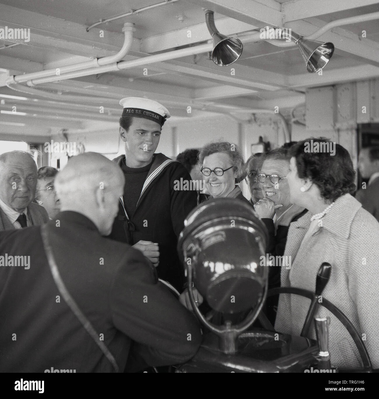 1950, historische, glücklich Kreuzfahrtpassagiere stand neben einem uniformierten Seemann an Bord der P&O Versand, SS Chusan, einer britischen Ocean Liner. Stockfoto