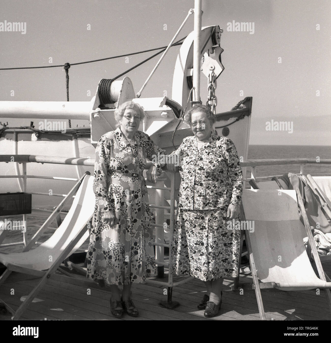 1950, historische, Kreuzfahrt auf dem Ozeanriesen in dieser Ära, zwei ältere Damen tragen Blumen gemusterte Kleider stehen draussen auf dem Deck des P&O Chusan Kreuzfahrtschiff. Stockfoto