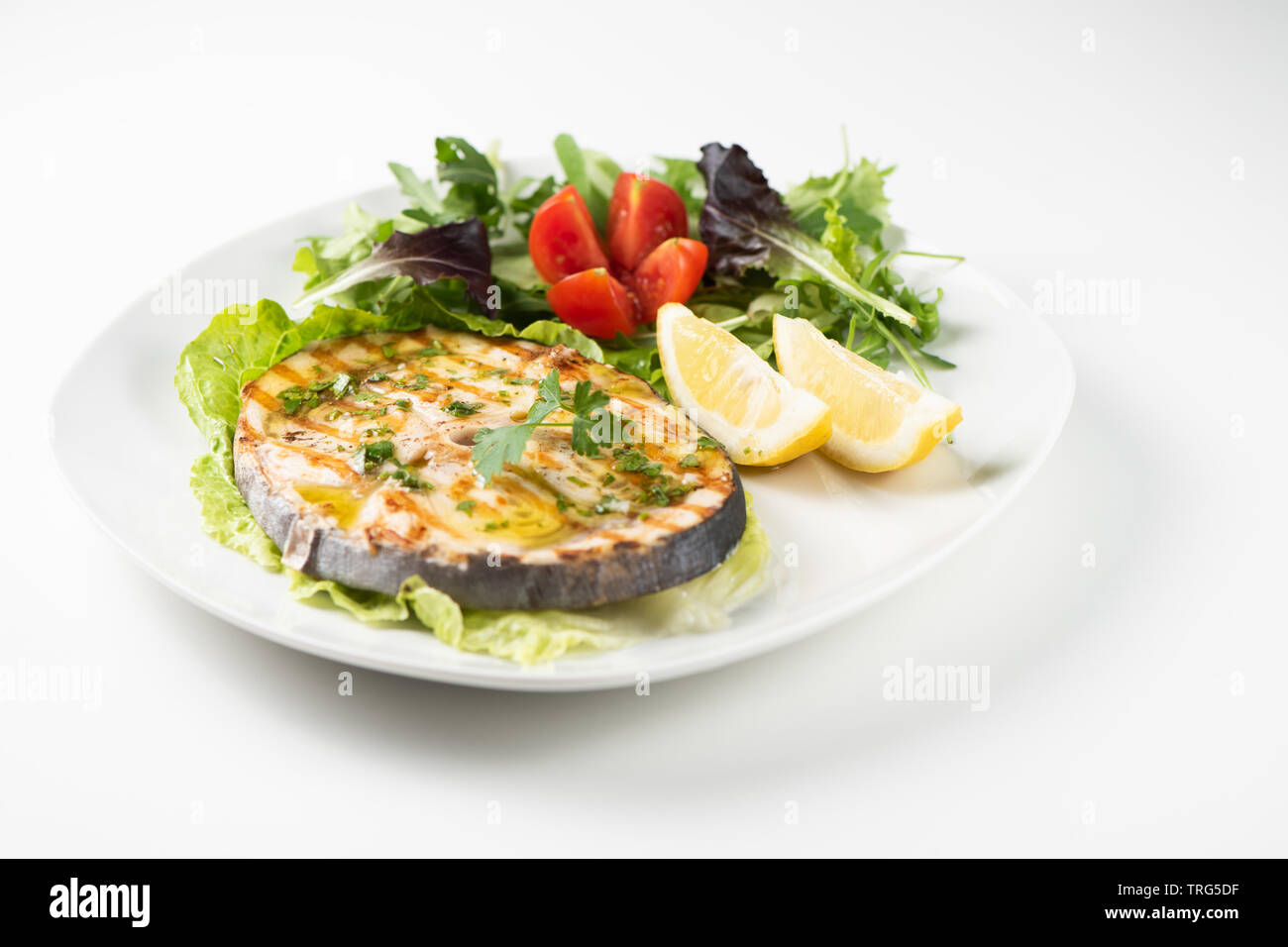 Gegrillter Schwertfisch mit Salat und Zitrone auf die weiße Platte. Nahaufnahme Stockfoto