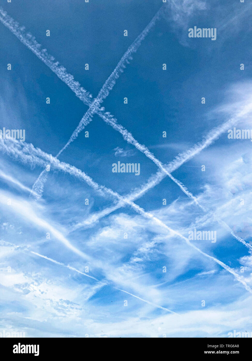 Criss-cross-Flugzeug Kondensstreifen außerhalb des Flughafens Heathrow auf einem englischen Sommer Tag. Juni 2019 Stockfoto