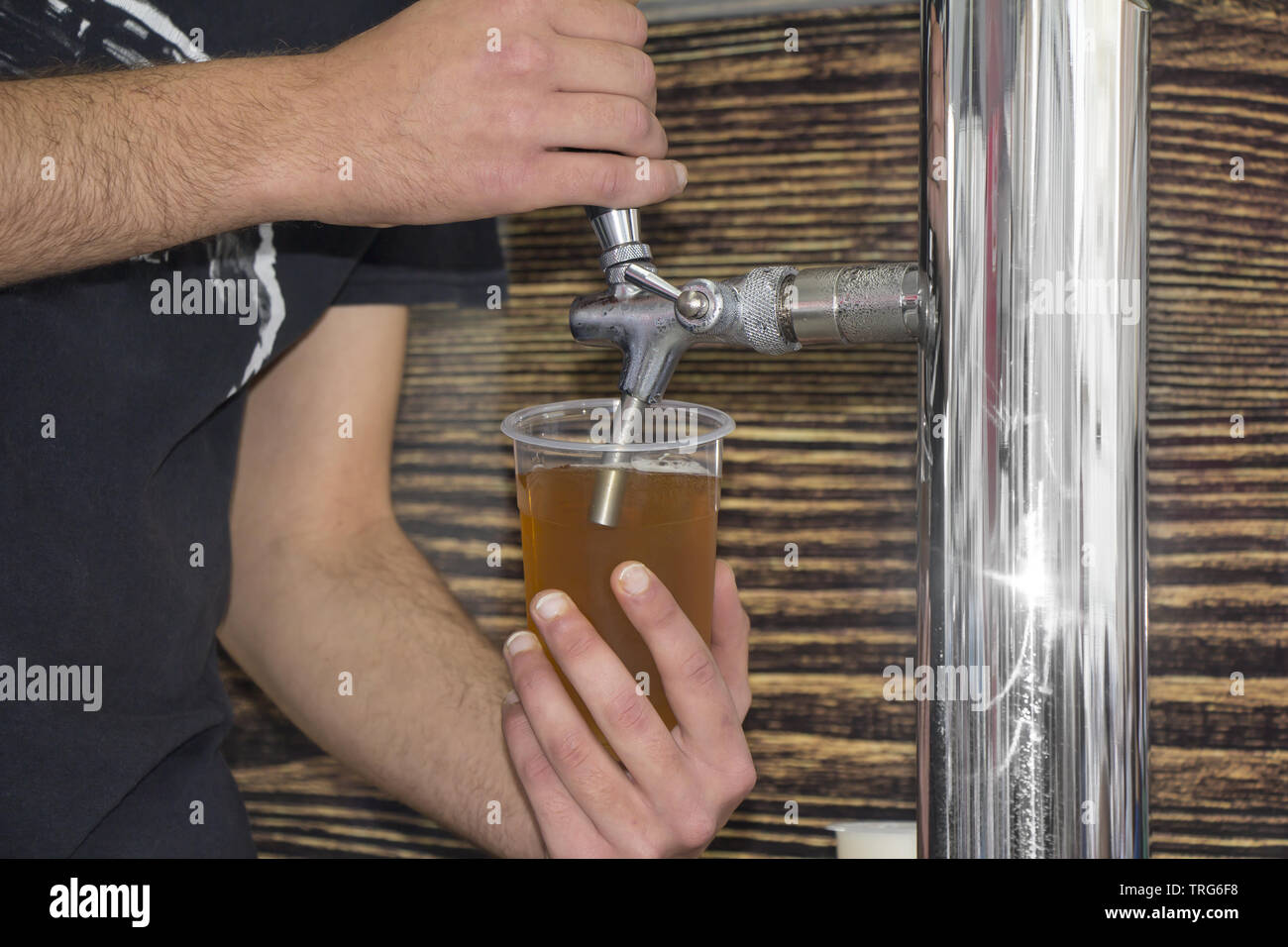 Barkeeper Füllung Kunststoff Glas mit hellen Bier Stockfoto