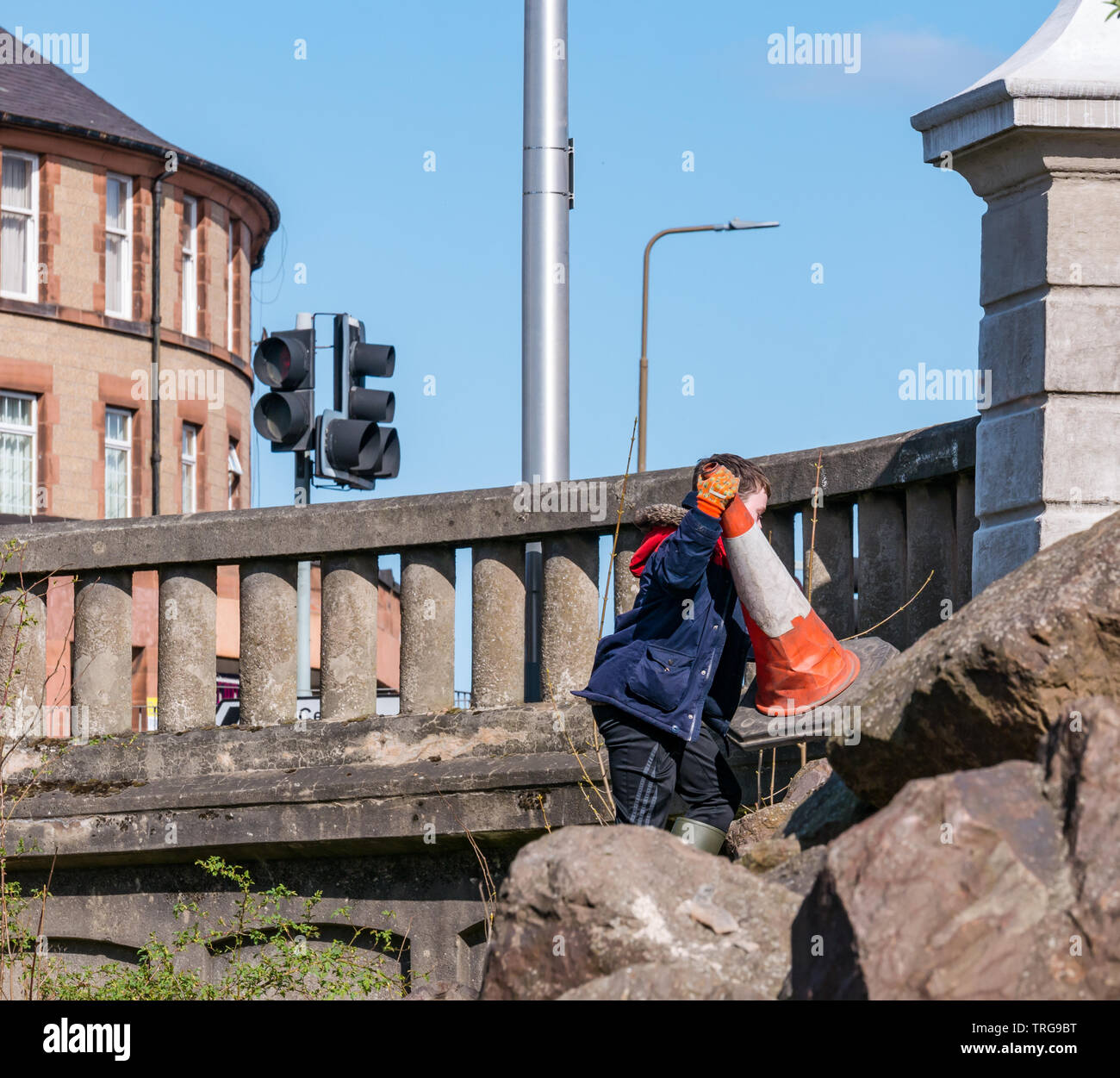 Freiwillige auf jährlichen Frühjahrsputz auf der Bank von Wasser von Leith, Edinburgh, Schottland, Großbritannien. Ein Junge ruft eine Leitkegel vom Flussufer Stockfoto
