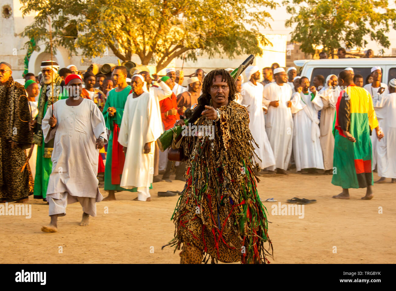 Sufi mit Dreadlocked Haar in schwere Perlen Kostüm mit Holz Imitation Gewehr an wirbelnder Derwisch Zeremonie vor Sonnenuntergang in Omdurman, Sudan Stockfoto