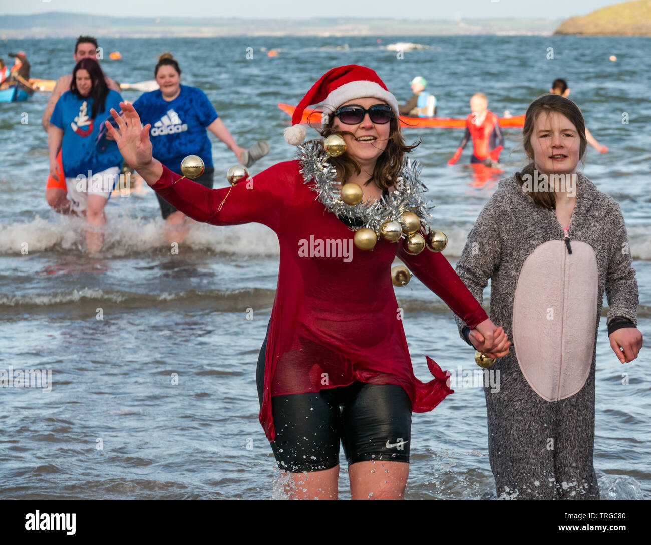 Loony Dook, Tag des Neuen Jahres: Die Menschen mutig kaltes Wasser der West Bay, Firth-of-Forth, North Berwick, East Lothian, Schottland, Großbritannien. Frau in Santa Hut Stockfoto