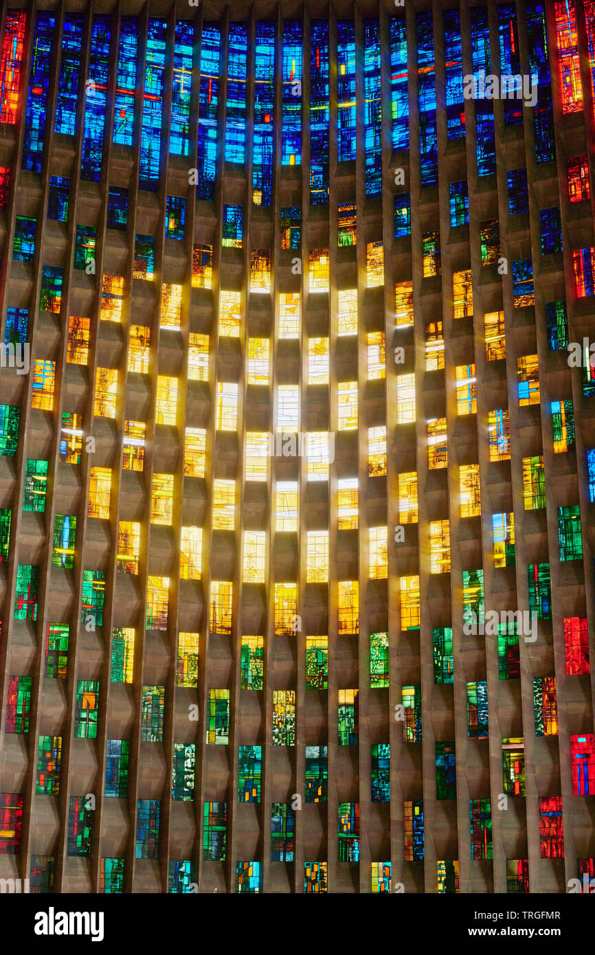 Bunte Glasfenster hinter dem Stein Schrift im Baptisterium der Kathedrale in Coventry, England. Stockfoto