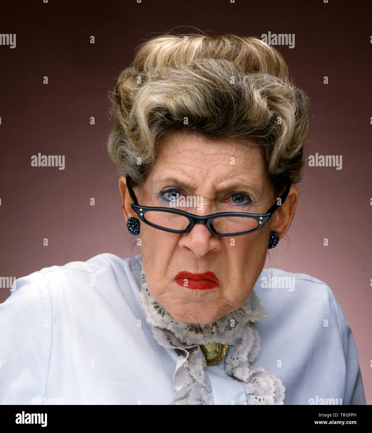 Mürrische alte Dame mit Brille Stockfoto