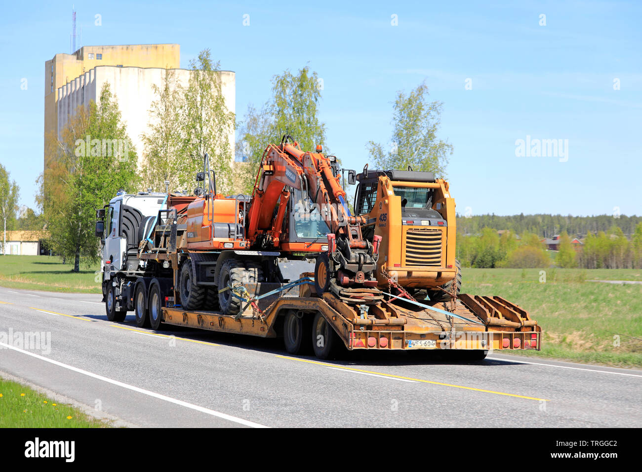 Salo, Finnland - 17. Mai 2019: Renault Trucks semi schleppt eine große Last von Baumaschinen auf Anhänger entlang der Straße an einem Tag im Frühling, Ansicht von hinten. Stockfoto