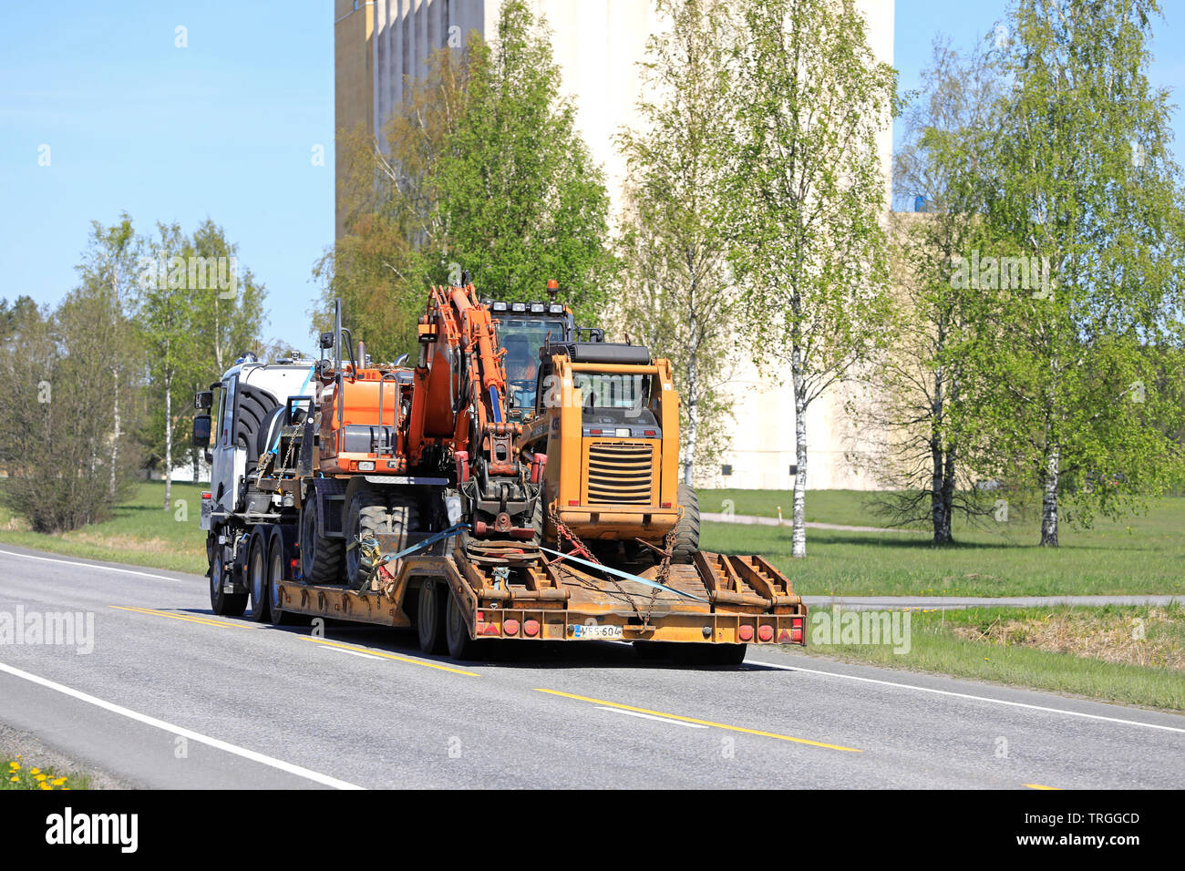 Salo, Finnland - 17. Mai 2019: Renault Trucks semi schleppt eine große Last von Baumaschinen auf Anhänger entlang der Straße an einem Tag im Frühling, Ansicht von hinten. Stockfoto