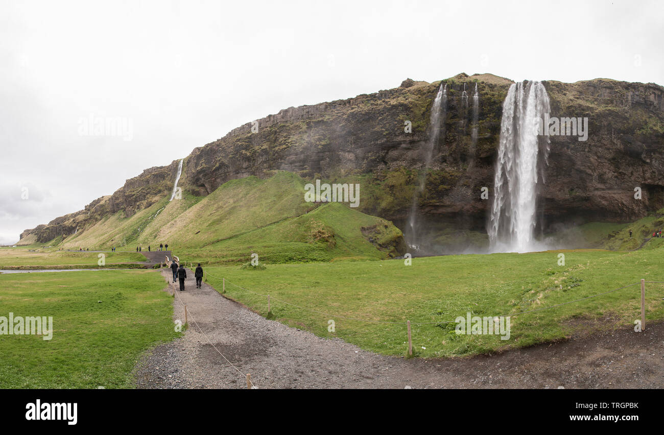 SELJALANDSFOSS, Island - 30. Mai 2018: Touristen zu Fuß auf einem Weg in der Nähe des Seljalandsfoss an einem bewölkten Tag. Nur für den redaktionellen Gebrauch bestimmt. Stockfoto