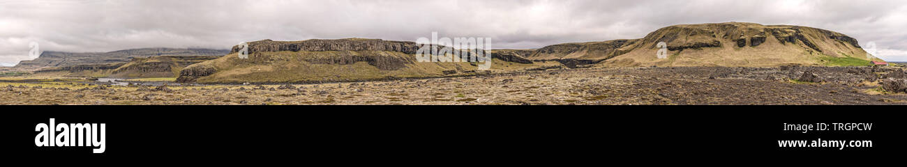 Extra-Long Panoramablick auf Djúpá River im Süden Islands mit Bergen, Felsen und Nebel, und einige Bauernhöfe und ein Wasserfall in der Ferne. Stockfoto