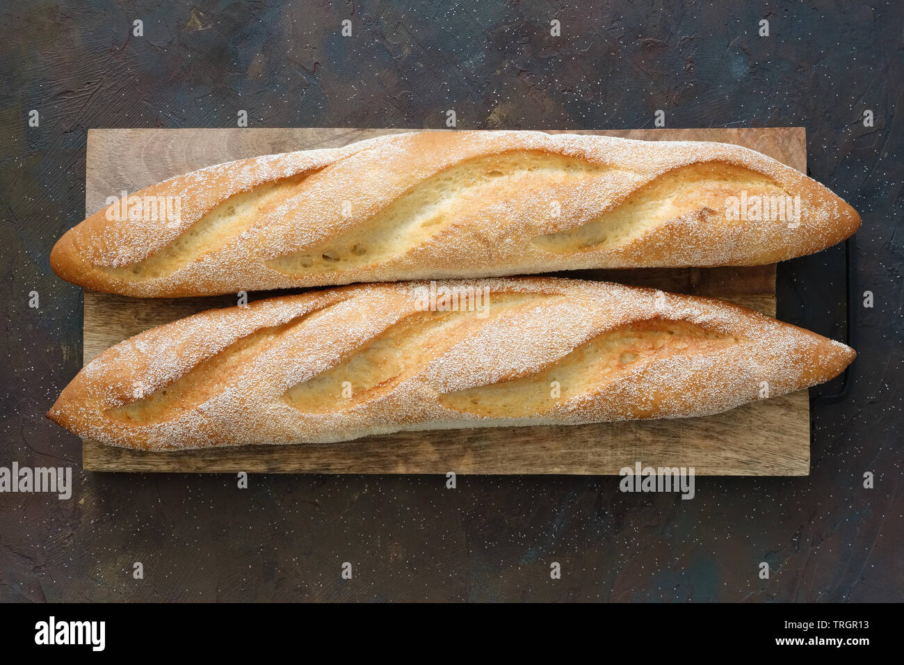 Zwei frisch gebackene Baguettes auf Schneidebrett. Ansicht von oben. Stockfoto