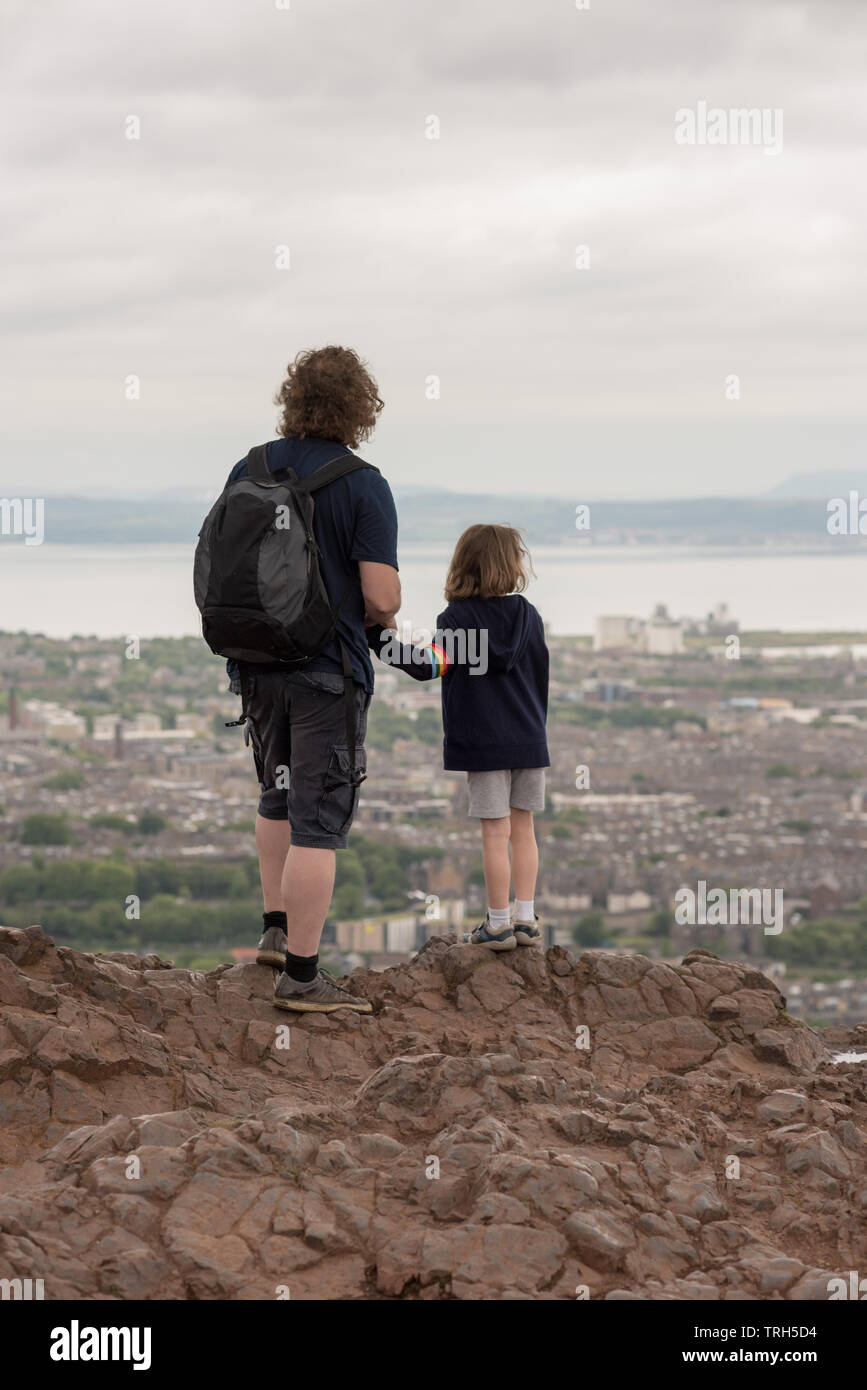 Ein Mann und ein Kind bewundern Edinburgh vom Gipfel des Arthur's Seat. Stockfoto