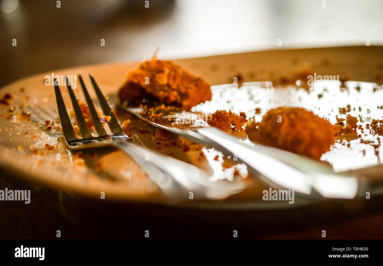 Messer und Gabel auf einen leeren Teller mit Essensresten und Krümel Stockfoto