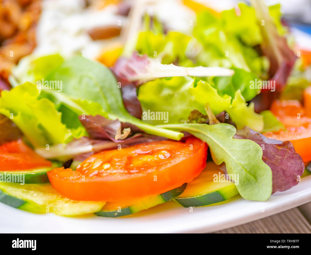 In der Nähe von Tomaten, Oliven, Schafskäse und Scheiben Gurken aus einer berühmten griechischen Salat, gegen einen verschwommenen Hintergrund. Horizontale Ansicht Stockfoto