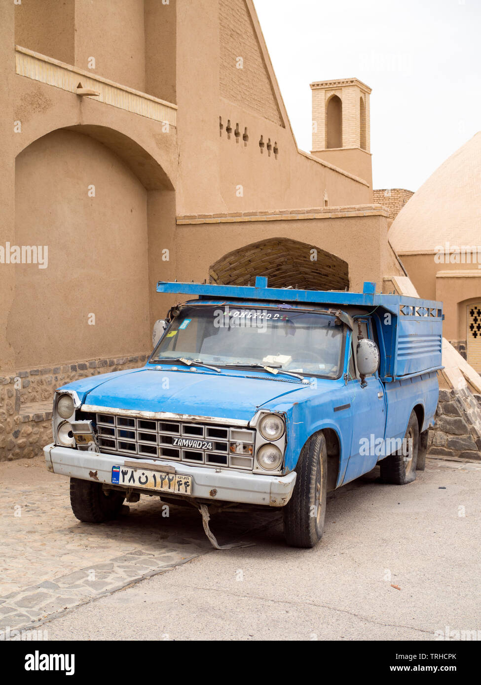 Einen alten blauen Lkw vor einem restaurierten Teil der alten Stadt in Aqda, Iran. Stockfoto