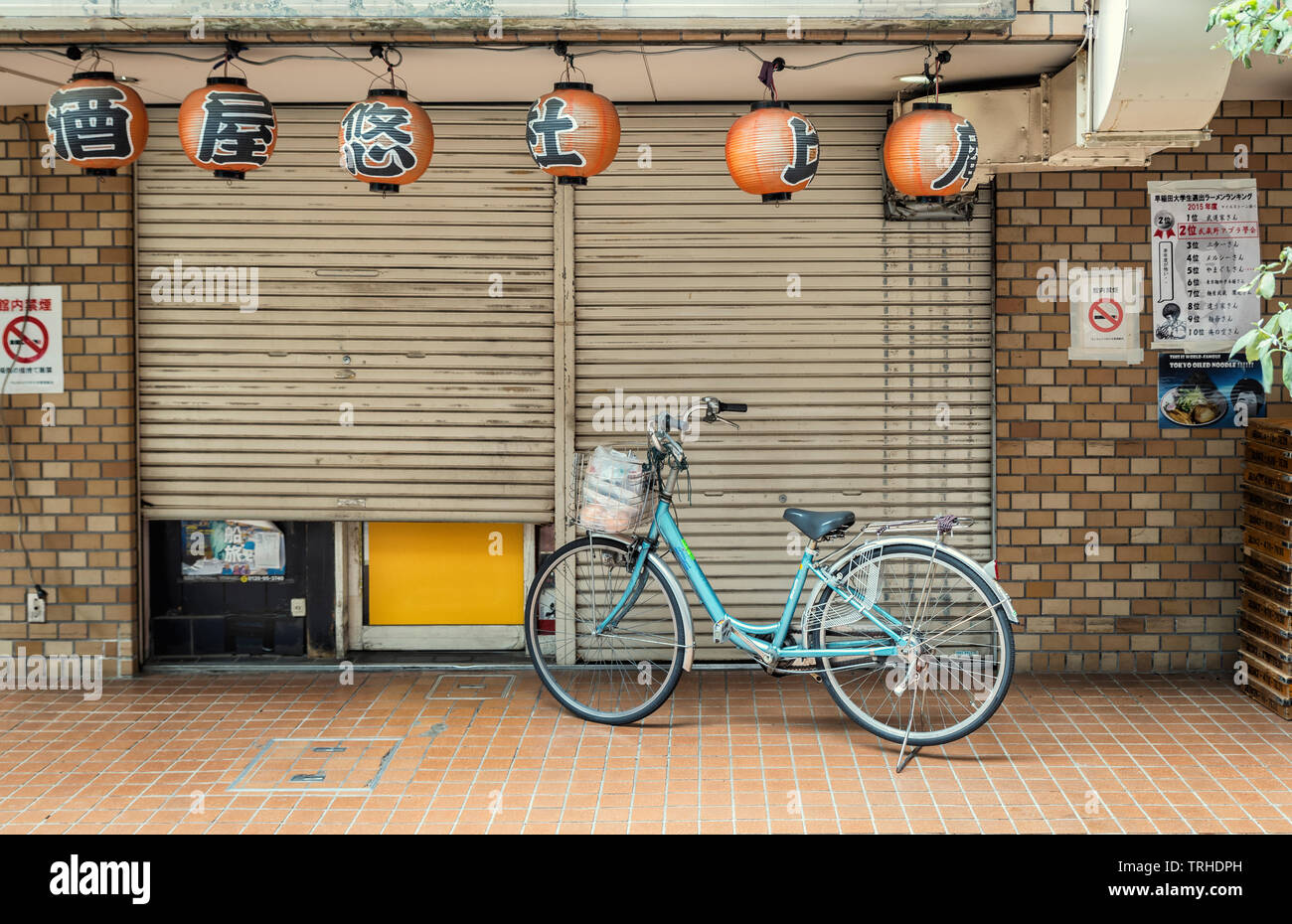 Ein einzelnes Fahrrad außerhalb einer geschlossenen Shop in Tokio, Japan. Japanische Laternen hängen an der Vorderseite der Shop Stockfoto