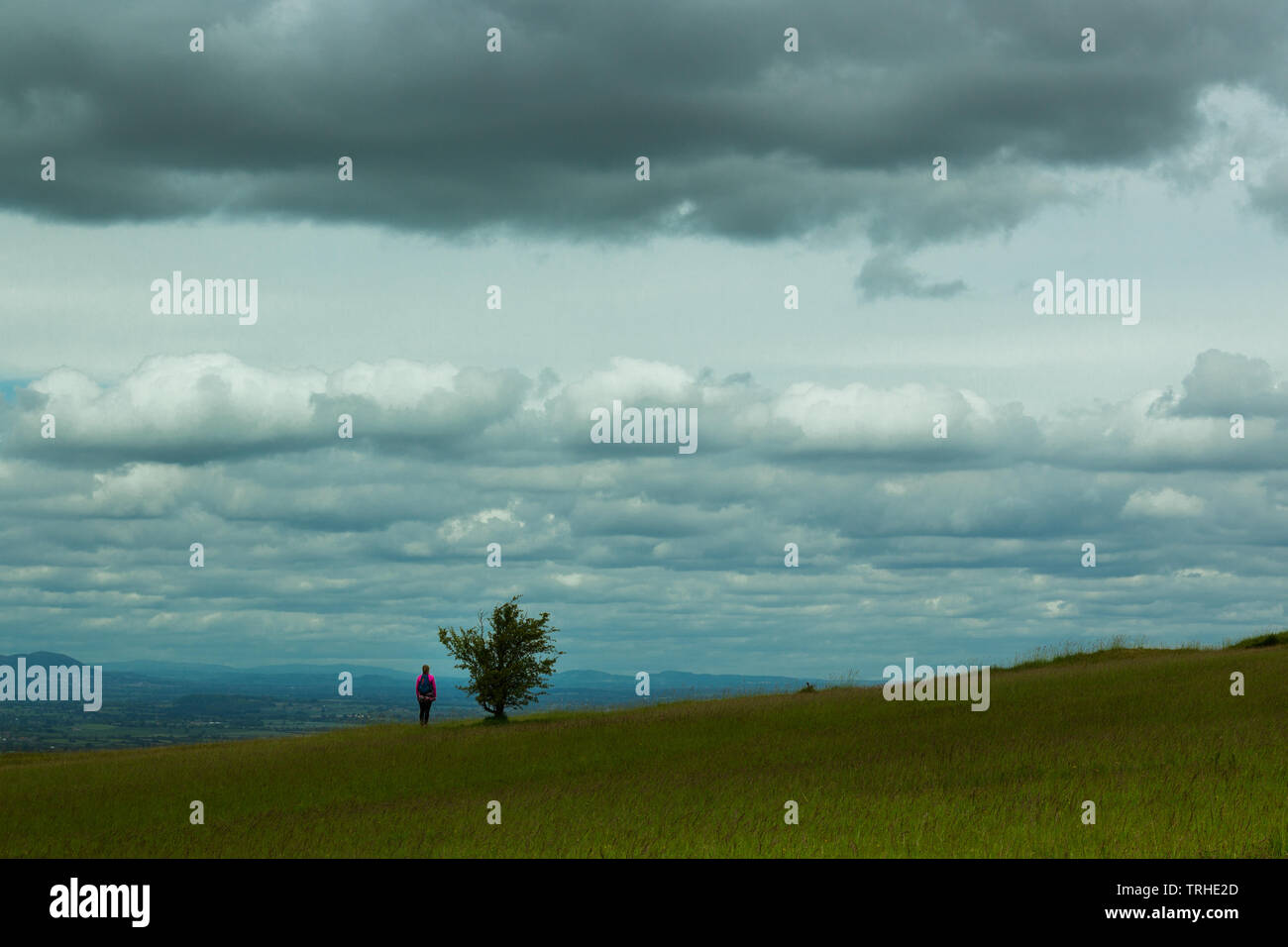 Ein einsamer Wanderer hält den Blick über die weite Landschaft auf die fernen Hügel auf einem blustery, bewölkter Tag zu bewundern. Stockfoto