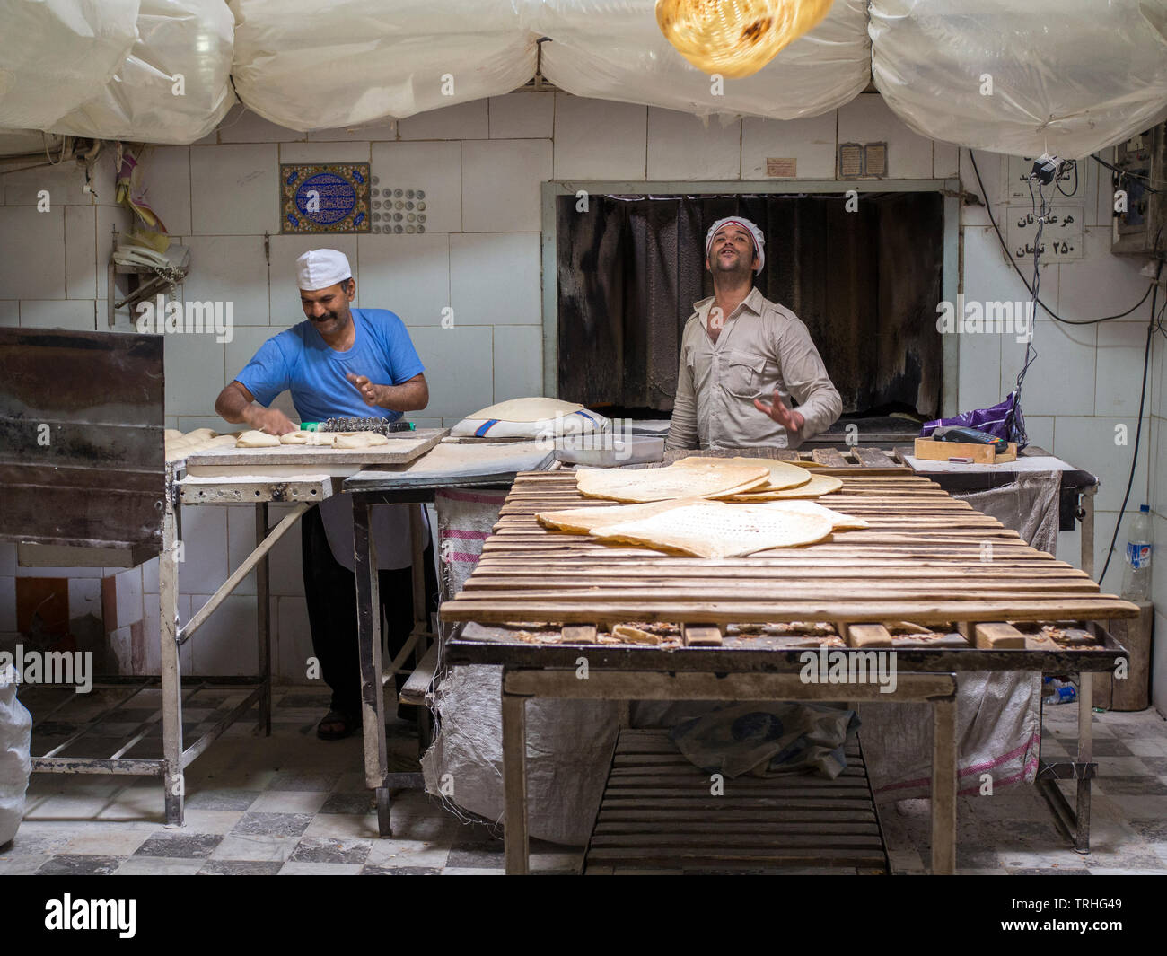 Ein Bäcker wirft eine Festplatte von Naan Brot in die Luft an seiner Bäckerei im Basar, oder Marktplatz, in Yazd, Iran. Stockfoto