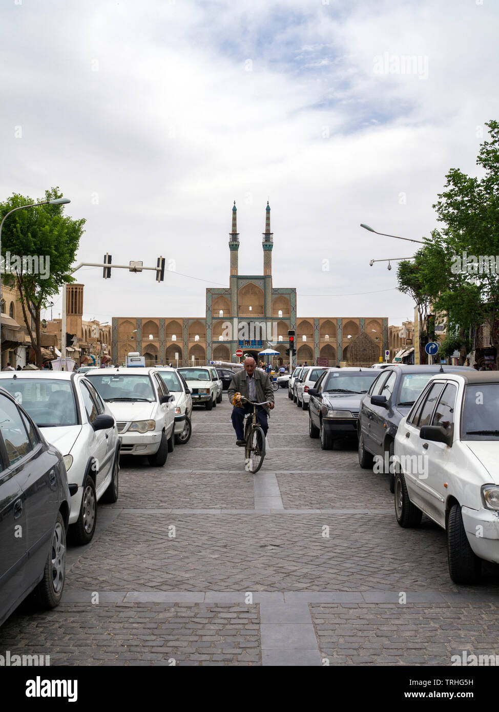 Ein Mann Radfahren zwischen parkenden Autos vor der Amir Chakhmaq Komplexe in der Altstadt von Yazd, Iran. Stockfoto