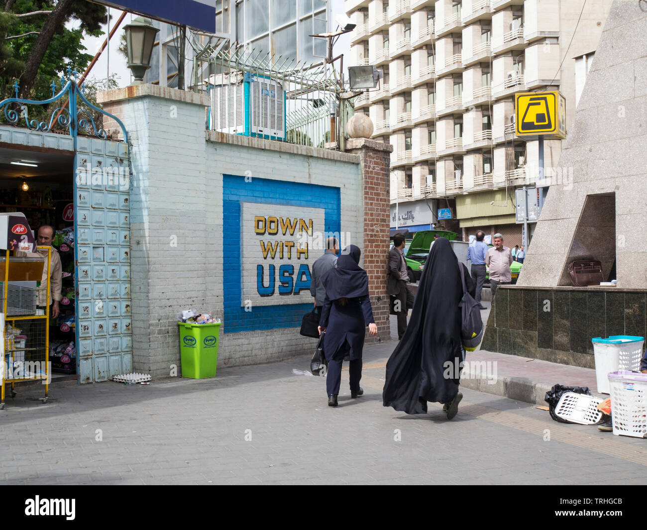 Pendler halten an der Mauer vor der ehemaligen US-Botschaft in Teheran einen Slogan, der zur Zerstörung Amerikas aufruft. Stockfoto
