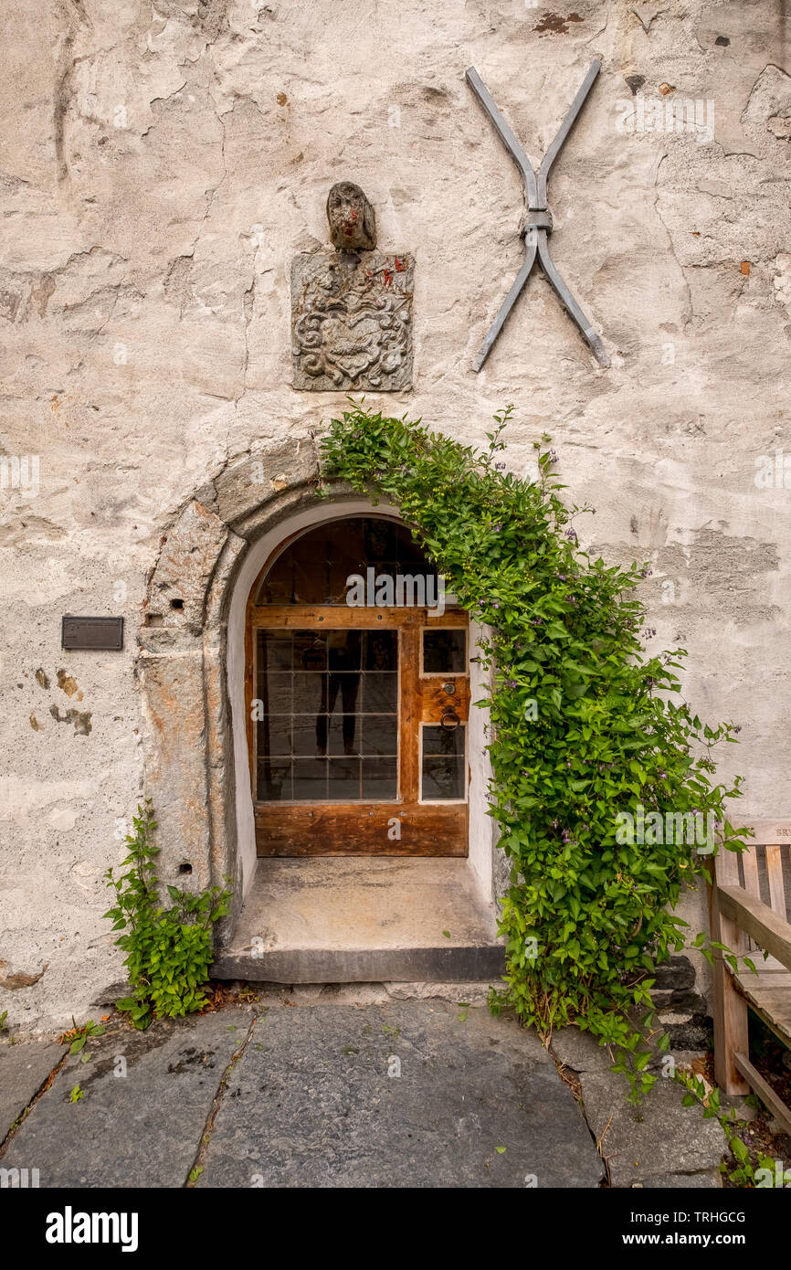 Haus aus Stein mit romantischen hölzerne Eingangstür mit Fenster, mit einem Eisen Herz und ein eisernes Kreuz dekoriert, mit Efeu, Bryggen, Bergen begrenzt. Stockfoto