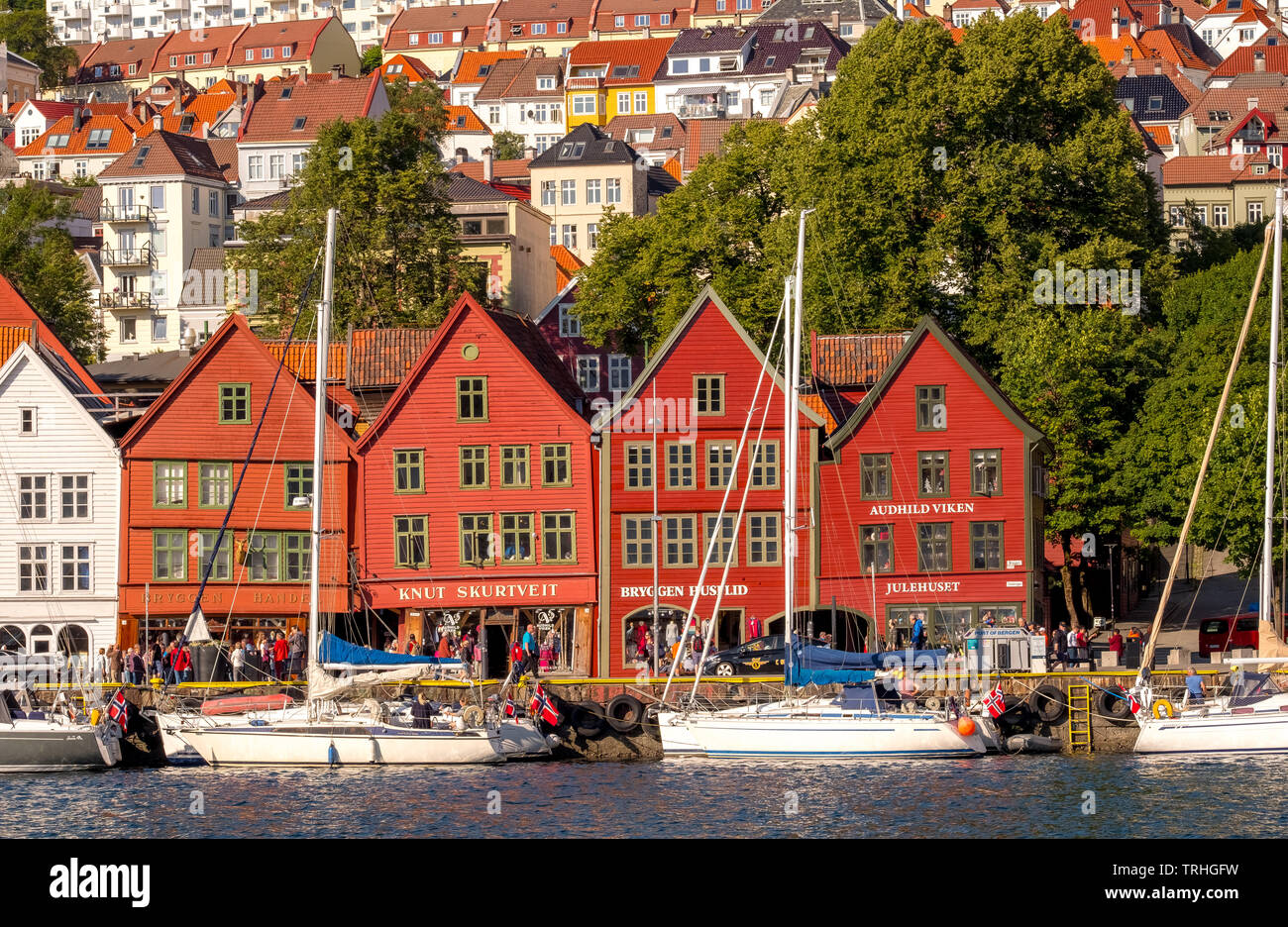 Nordsee, hinter einer bunten Holzhäusern vorne mit angehängten Segelboote im Hafen von Bryggen, über andere Häuser der Stadt, Bergen, Hordaland, Stockfoto