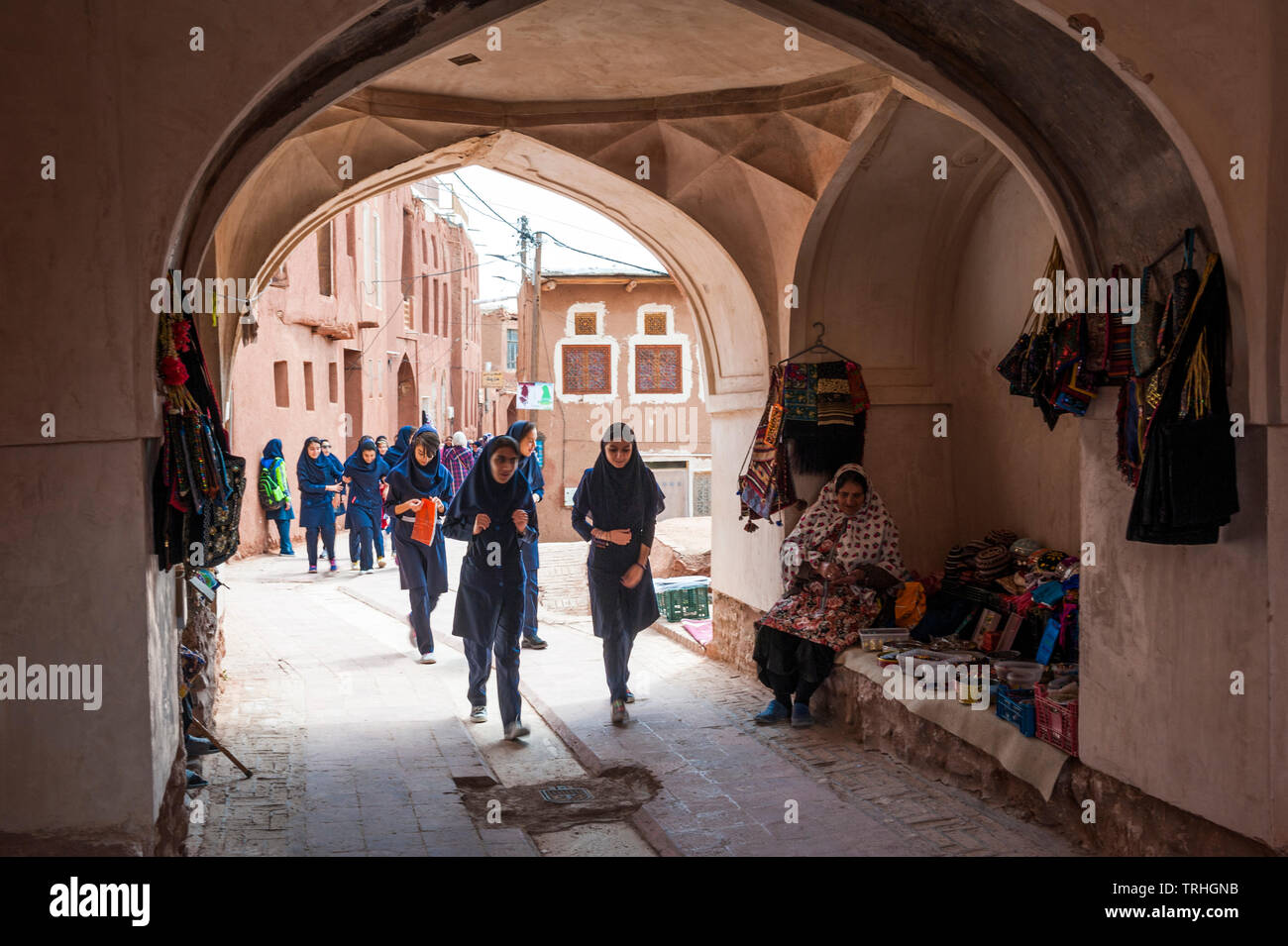 Eine Gruppe von Mädchen zu Fuß durch einen Torbogen in der Altstadt von Abyaneh, Iran. Die Stadt ist eine beliebte Touristenattraktion. Stockfoto