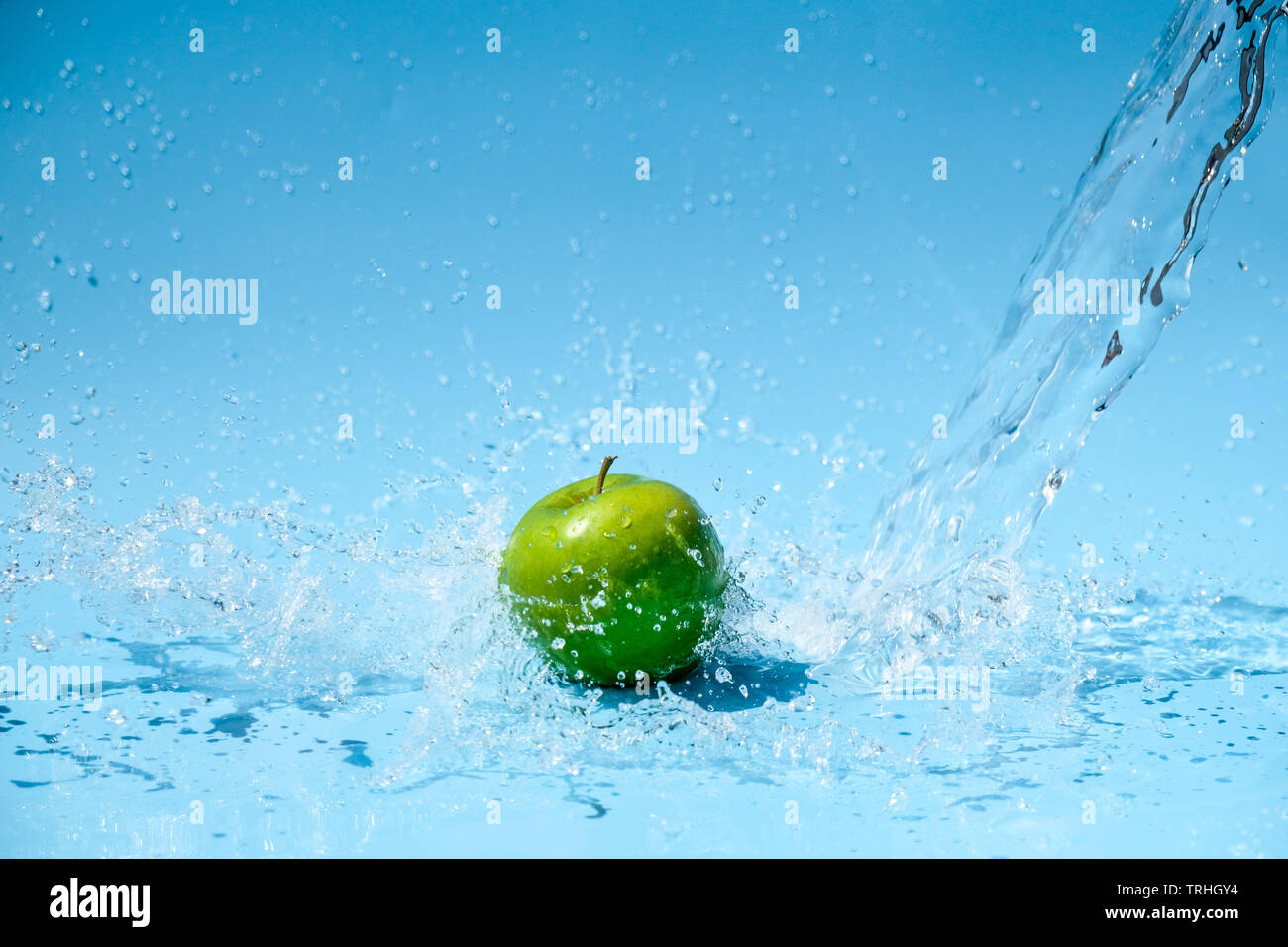 Grüner Apfel im Wasser Spritzer auf blauem Hintergrund Stockfoto