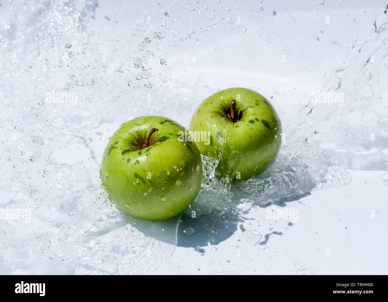 Zwei grüne Äpfel im Wasser spritzen auf weißem Hintergrund Stockfoto