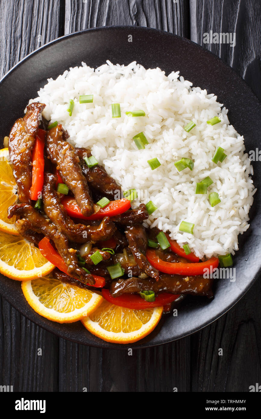 Asiatische Rindfleisch Rühren braten mit Paprika in Soja orange Sauce mit Reis close-up auf einem Teller auf den Tisch serviert. Vertikal oben Ansicht von oben Stockfoto