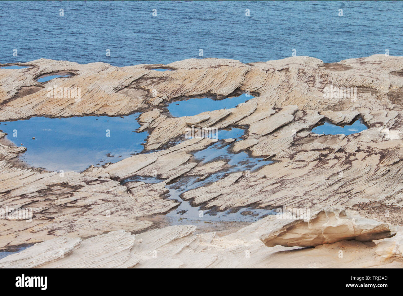 Pfützen mit Sky Reflexion Meer Hintergrund und kleinen Stein im Vordergrund Stockfoto