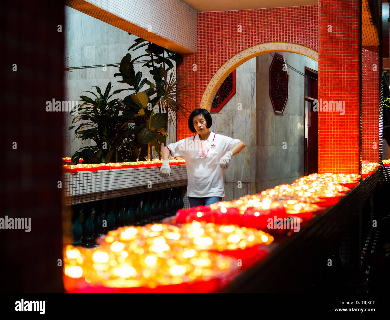 Singapur, 18. Mai 2019 - Ein freiwilliger Helfer in einem buddhistischen Tempel Spaziergänge Vergangenheit eine Reihe von Buddhistischen Öllampen auf Vesak Day Stockfoto