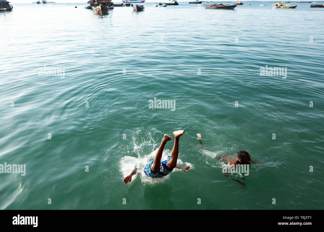 Teenager schwimmen und tauchen aus den konkreten Seawall in den Indischen Ozean in Stonetown, Sansibar, Tansania. Stockfoto