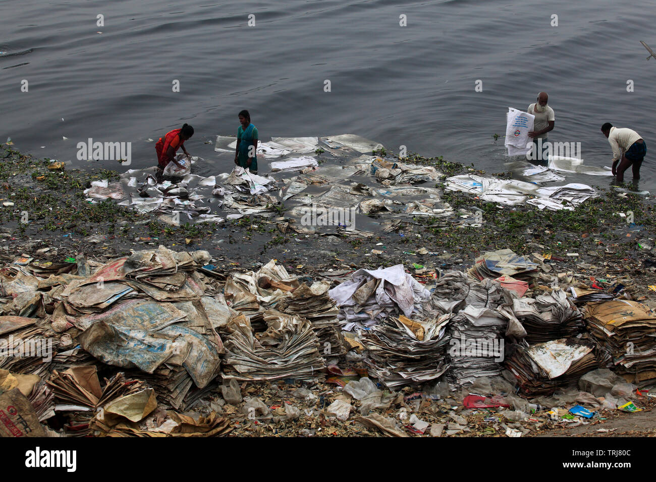 Arbeiter waschen Polyäthylenbeutel, die benutzt wurden, um Chemikalien zu tragen, in der buriganga Fluss für das Recycling. Dhaka, Bangladesch Stockfoto