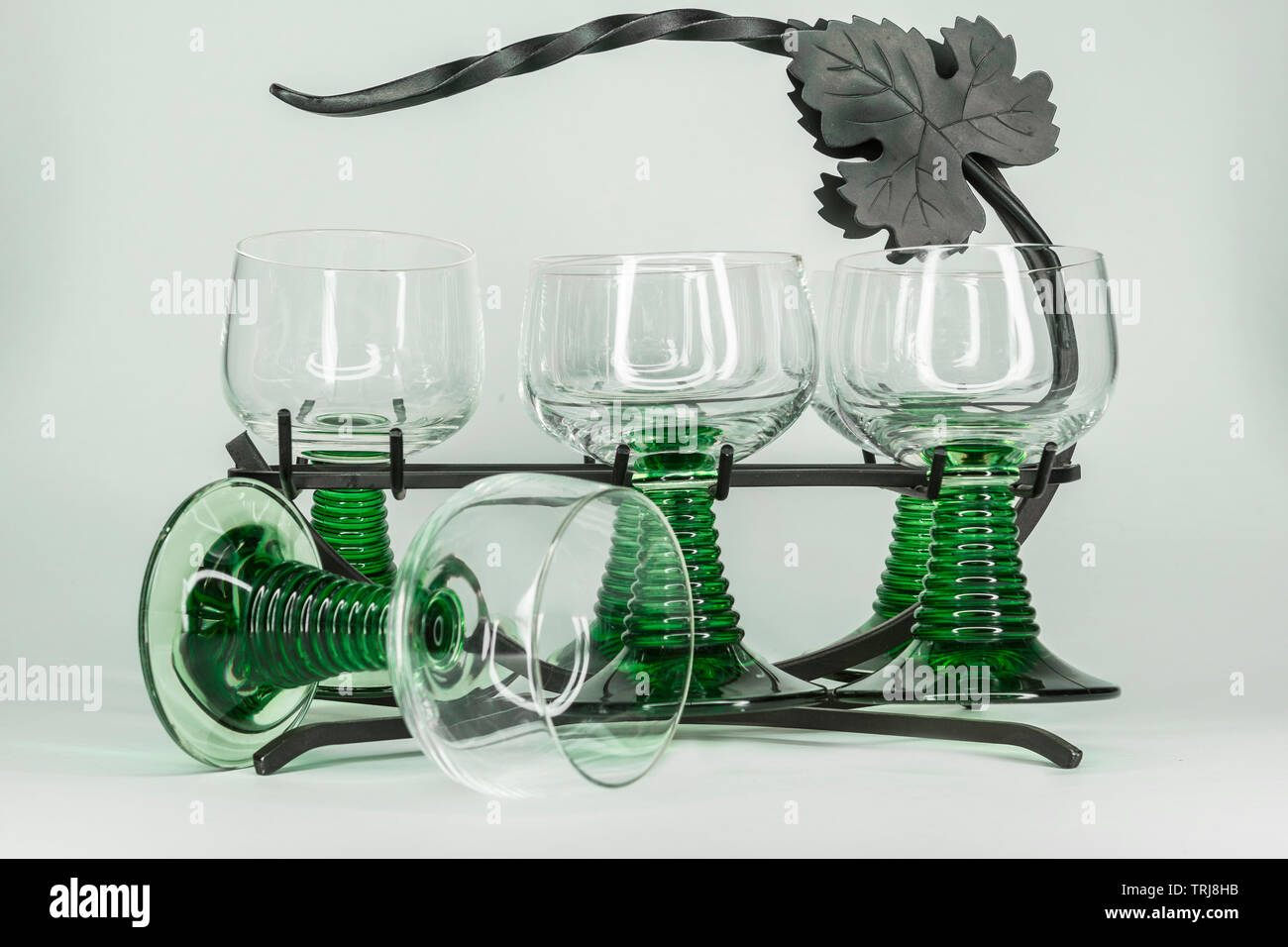 Fünf grüne Weingläser mit welligen grünen Stengel sitzen in einem  schmiedeeisernen Gestell mit ein Glas umgekippt Stockfotografie - Alamy