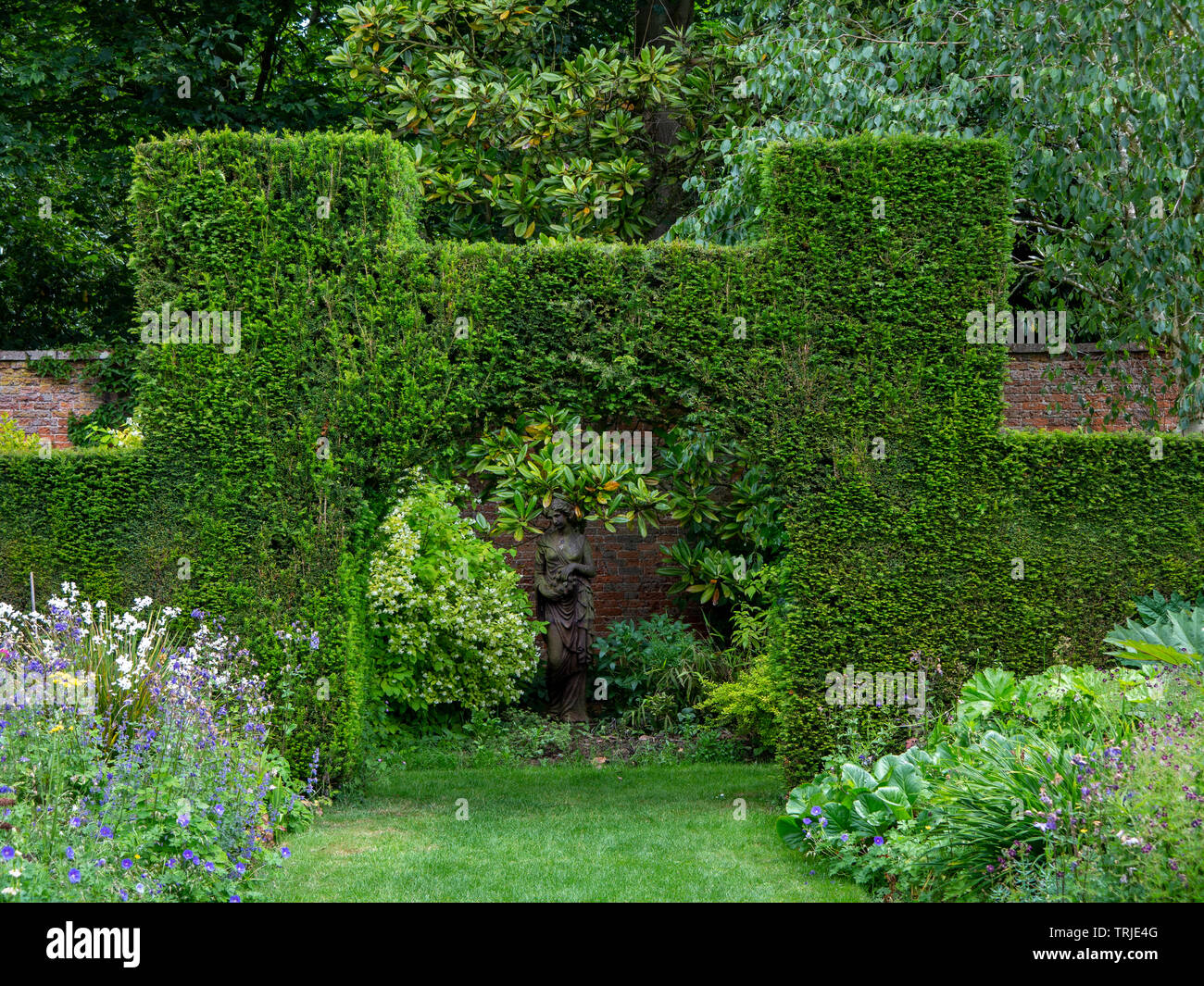 Formgehlze Torbogen in einer Eibe hedge Framing eine weibliche Figur  Garten statue gegen eine Red brick wall, den ummauerten Garten, Suffolk,  Grobritannien Stockfotografie - Alamy
